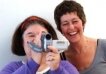 Two women, one trying out a camera, the other one laughing 