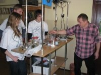 Three students with their teacher experimenting in a physics laboratory